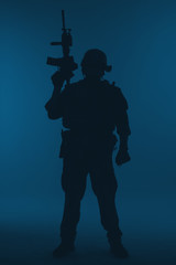 Fototapeta premium United states Marine Corps special operations command Marsoc raider with weapon. Silhouette of of Marine Special Operator blue background full body