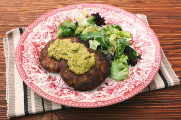 Fried beef patties with pesto sauce and greens