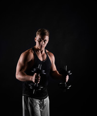 Fototapeta na wymiar Fitness trainer with dumbbells on black background. Man making training exercises. Concept of healthy life. Strong person look to the camera.