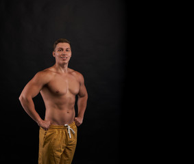 Fototapeta premium Happy smiling bodybuilder stay and look to the camera on dark background with naked body. Trained person shot. Health and sport life concept.