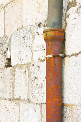 Old cast iron and copper downpipe against a stone wall