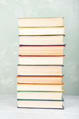 A stack of old colored books on shelf and green background