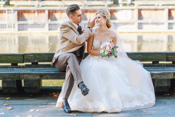 Naklejka premium The bride and groom are sitting on a bench in the city
