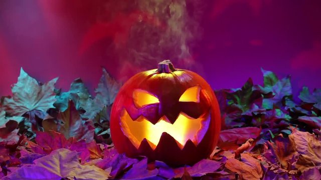 mystic Illuminated smoking halloween pumpkin with colored autumn leaves