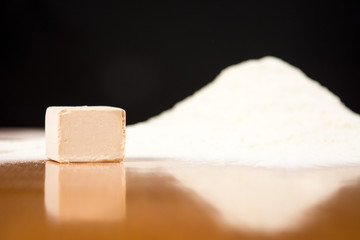 Yeast cube and flour pile on baking table