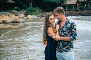 beautiful young couple in love holding their hands and walking on the beach, looking at the sea.  landscape. Concept of honeymoon