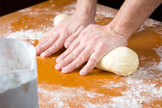 Man kneading dough on flour covered table