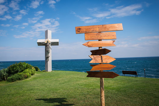 Picture of wooden direction signpost in front of the sea and grass