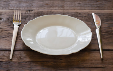 Plate with a fork and knife on a wooden background