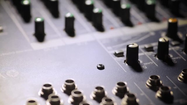 Vertical dolly shot video of a mixer desk with many buttons, with focus transition.