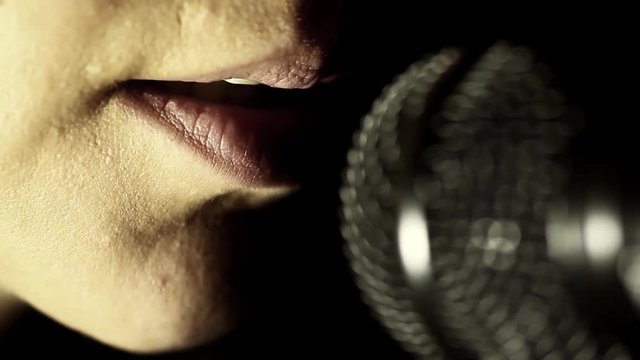 Close up footage of a woman singing to a microphone.