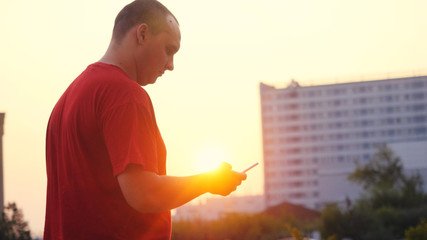 Man walking alone outdoor at sunset with smartphone