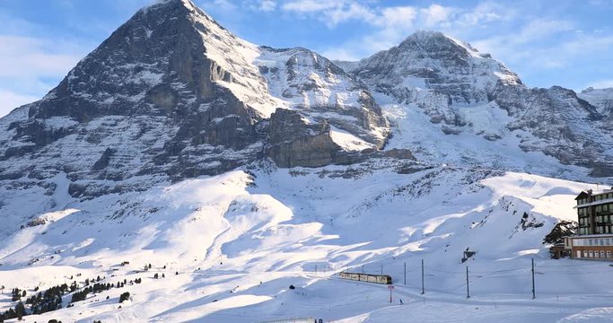 Famous electric yellow tourist train in Kleine Scheidegg train station under Eiger, Jungfrau and Monch in Swiss Alps
