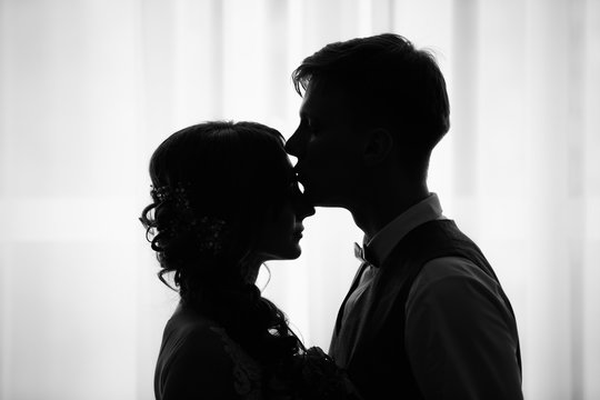 Silhouette of kissing bride and groom. Black and white wedding photo