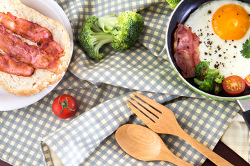 Breakfast with fried egg and bacon in dark pan on the table
