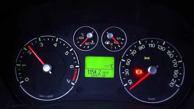 Color close up footage of a car's tachometer moving.