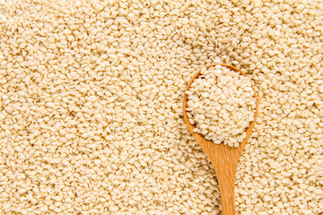 close up sesame in wooden spoon on white sesame seeds surface 