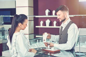 Fototapeta premium Jeweler showing for buyer necklace of gold jewelry set.