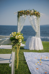 wedding ceremony flowers, arch, chairs with black sea in the background. Beach wedding