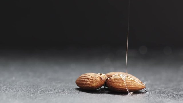 Slow motion of honey pouring over almond on slate board, 180fps prores footage