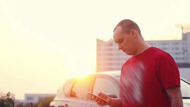 Young businessman walking alone outdoor at sunset with smartphone in slowmotion. Sun flare effects. 1920x1080