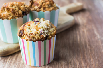 Three muffins in stripy paper cases on the wooden table, selective focus