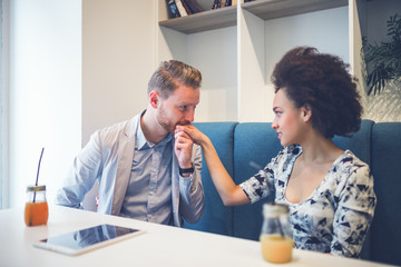 Obraz premium Happy middle age interracial couple sitting in cafe bar. Man giving Valentine's day gift to his girlfriend or wife. 
