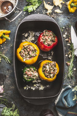 Colorful bell stuffed paprika peppers  in iron cooking pot  on dark rustic kitchen table...