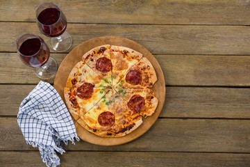 Italian pizza served in a pizza tray with red wine