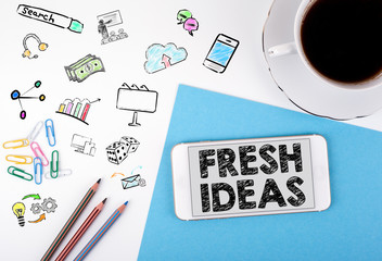 Fresh Ideas. Mobile phone and coffee cup on a white office desk.