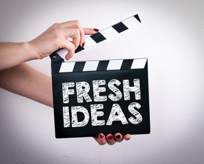 Fresh Ideas concept. Female hands holding movie clapper. 