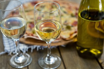 Wine glasses served with pizza in the background