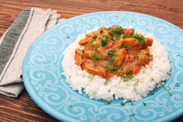 Rice with meat in tomato sause on wooden background
