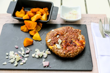 Grilled minced steak of beef with onions and fried potatoes on a