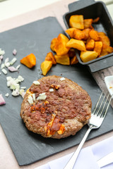 Grilled minced steak of beef with onions and fried potatoes on a