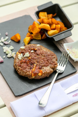 Grilled minced steak of beef with onions and fried potatoes on a