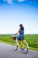 back view of woman riding retro bicycle in countryside