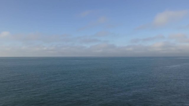 Time lapse. White clouds on the blue sky over the blue ocean.