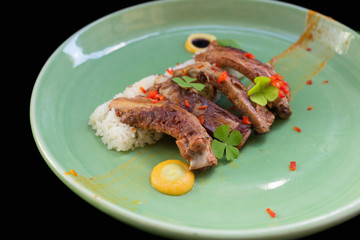 Grilled pork ribs and rice on plate black background.