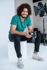 Happy photographer holding a camera in the studio