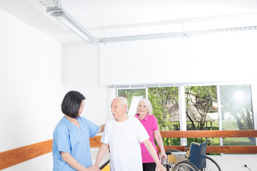 Nurse assisting elderly coiple in legs rehab