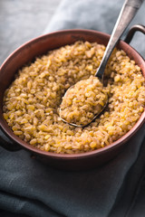 Bulgur in a copper bowl and metal spoon on the napkin