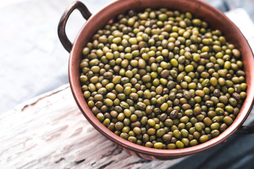 Beans in a copper bowl on a white stand