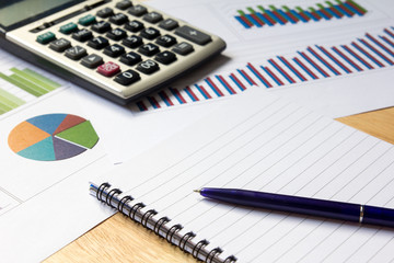Blank note book with financial graph, calculator and pen backgro