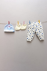 Baby apparels on clotheslines on plain gray background. Shot on portrait format.