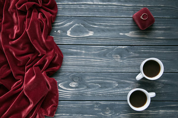 Set of red velor, ring on jewelry box and two white coffee cups on grey background. Space for text