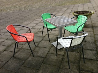 Sitzgruppe mit Plastikstühlen in den Farben der italienischen Trikolore vor einem Eiscafé am...
