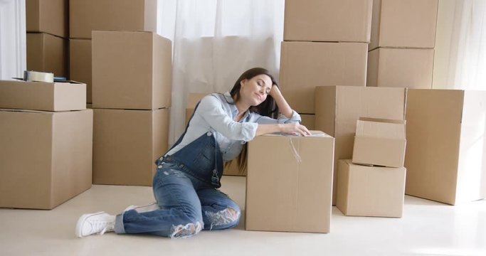 Tired young woman taking a break from packing up her belongings in boxes to renovate her apartment