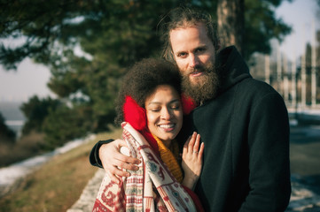 Romantic multiethnic couple in love hugging on the street