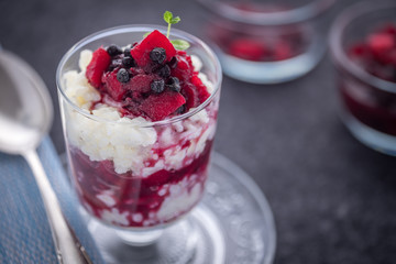 Milchreis im Glas mit rotem Kompott aus Äpfeln und Blaubeeren